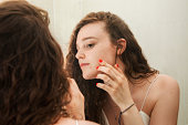 Young teenager looks in the mirror while checking her face. Concept of health, beauty and adolescence
