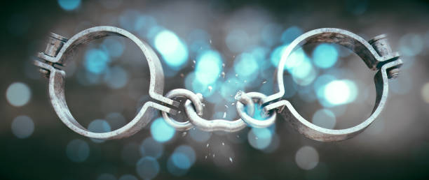 istock Old fashioned metallic handcuffs with a broken chain link, isolated on a dramatic illuminated background. 1341536511