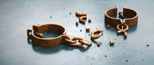 Vintage rusty iron handcuffs with chain, lying down unlocked and broken into many pieces. Close-up, wide horizontal composition.