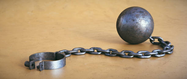 istock A chain and ball with open fetters lying down on a dirty surface. 1341536762