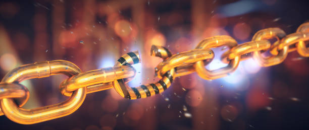 istock Gold-colored chain in the process of dramatically breaking into many scattered pieces, on an industrial backdrop. Wide horizontal composition. 1341536776