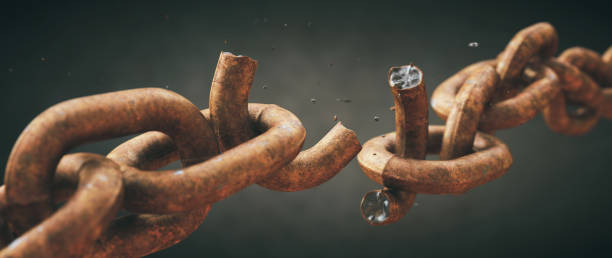 Rusty old chain broken in two with focus on the crumbling link, isolated on a dark defocused background. Wide horizontal composition. Rusty old chain broken in two with focus on the crumbling link, isolated on a dark defocused background. Wide horizontal composition. rusted chain stock pictures, royalty-free photos & images