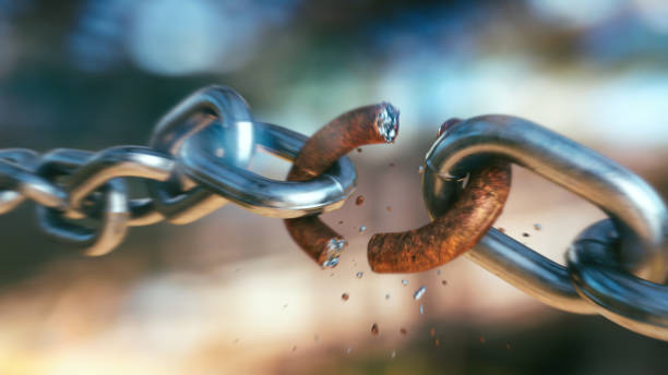 istock Dramatic close-up on a breaking chain with a rusty link and fragments flying off in blurred motion, on a defocused multi-colored background. 1341536873