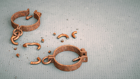 Medieval rusty iron handcuffs with chains, lying down unlocked and broken into many pieces.