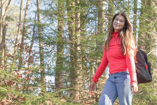 Young latin Woman portrait while doing trekking, hiking and walking on a pathway in the middle of pine crest forest in a cold autumn christmas morning day in Tennessee, United States of America.

She is wearing a red sweater, blue jeans, white shoes and carry a bag pack.

Christmas Holidays Concepts.
Christmas Holidays Portraits.
Young Latin woman Portraits living in United States of America.