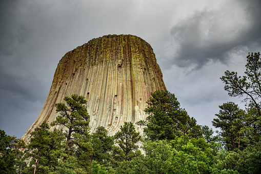 Low angle view of Devils Tower Monument under dark stormy sky