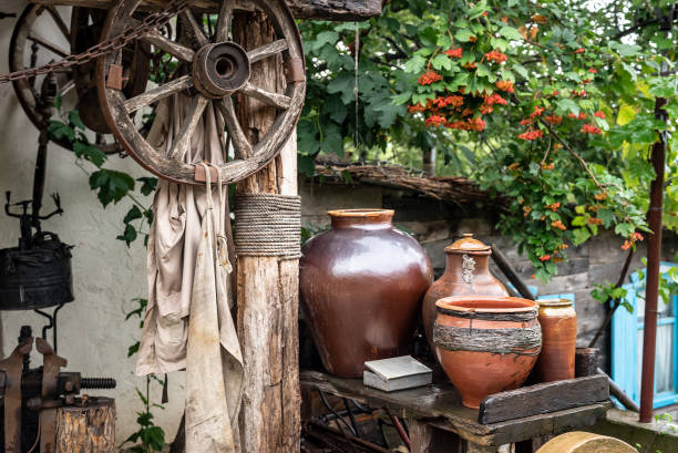istock Clay pots on rack by beam with hanging wagon wheels in yard 1341564712