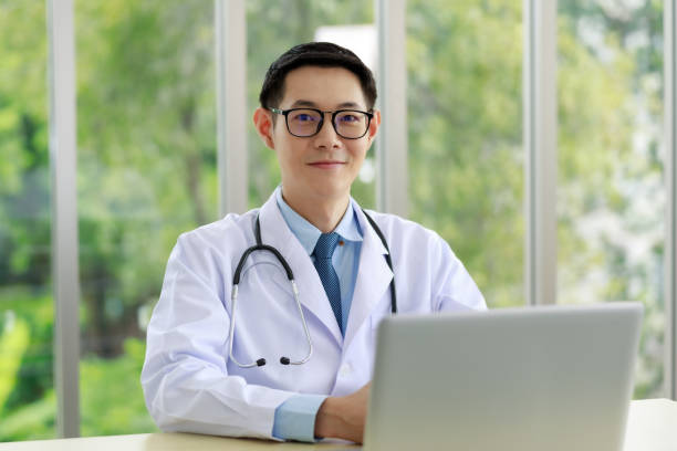 istock Portrait asian Doctor sitting and looking camera on work space and computer on the table in office hospital 1341575221