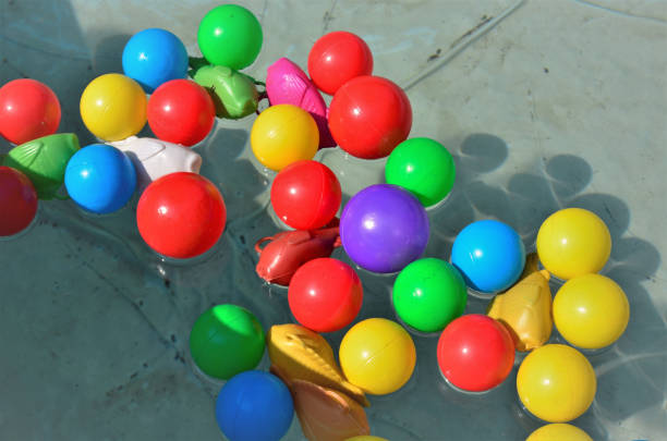 In the pool water several colored balls and plastic fish on sunny day