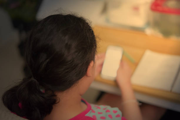 istock A black haired girl is using her mobile phone to search for information. doing homework on the table at home 1341589597