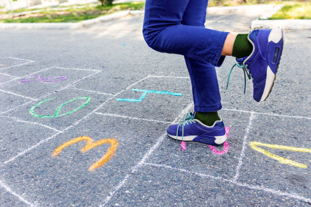 giochi per bambini di strada nei classici hopscotch. disegno con gesso colorato sull'asfalto. messa a fuoco selettiva. natura - little girls sidewalk child chalk foto e immagini stock