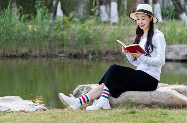 Young woman reading book by the lake.