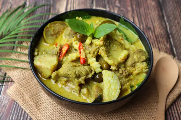 Photo of Thai green curry with beef served in bowl of the wood table - Thai food called Kang Keow Wan