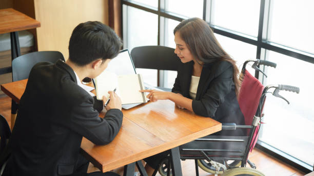 同僚と車椅子のブレーンストークで障害のある女性ビジネス従業員 - working people physical impairment wheelchair ストックフォトと画像