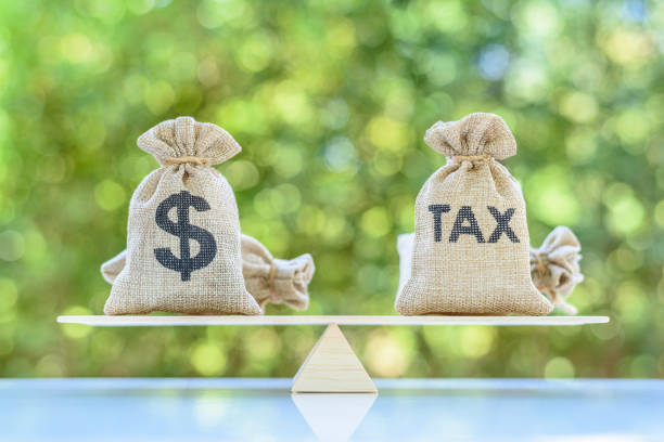 Tax, dollar money bags on a simple balance scale Income tax collection, strategy for paying tax, financial concept : The image depicting planning for reducing tax liability e.g investment and retirement tax stock pictures, royalty-free photos & images