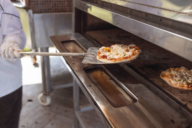 Chef takes out a hot pizza from the oven