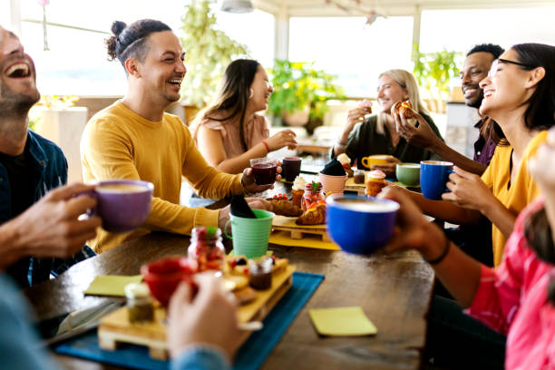 Smiling group of diverse friends having breakfast and talking at coffee bar stock photo