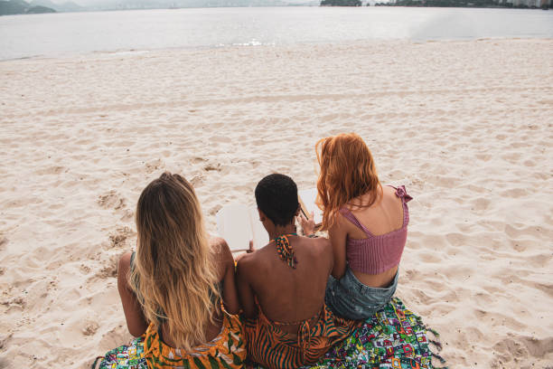 istock Friends relaxing at the beach with a books 1341607204
