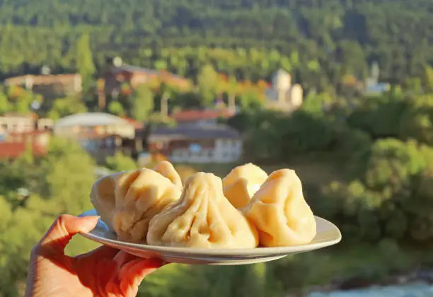 Photo of Plate of Georgian Traditional Soup Dumplings Called Khinkali in Woman's Hand