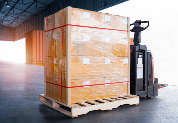 istock Package Boxes Wrapped Plastic Film on Pallet  with Electric Forklift Pallet Jack. Cargo Shipment Boxes Warehouse Logistics and Transportation. 1341609832