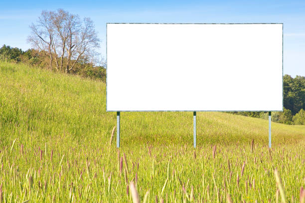 istock Blank advertising signboard in a green field with trees on background - concept  with copy space 1341611007