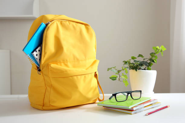 istock Yellow backpack and stack of notepads on table home. School supplies. Back to school concept. Educational design objects. Home studies. 1341614426