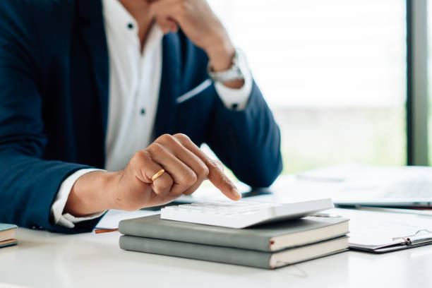 istock Businessman's hands with calculator at the office and Financial data analyzing counting on wood desk 1341619342