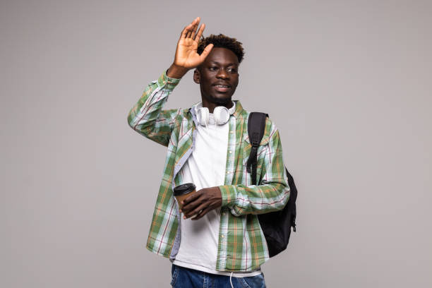 istock Young african man student with backpack wave with hands isolated on white background 1341620937