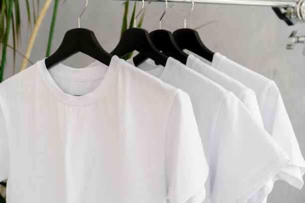 istock Row of white t-shirts on hangers on rack 1341621030