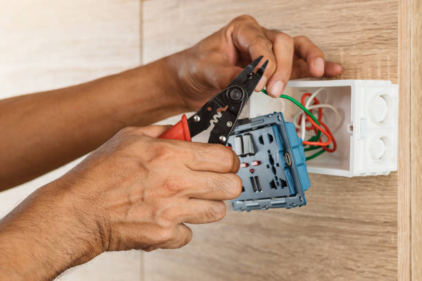 Electrician is stripping electrical wires in a plastic box on a wooden wall to install the electrical outlet. stock photo