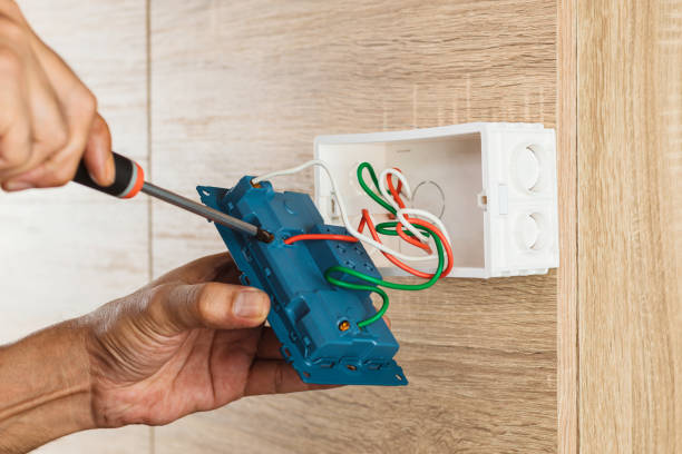 Hand of an electrician is using a screwdriver to attach the wires to the socket. stock photo