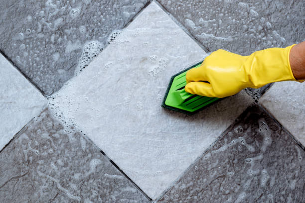 Cleaning the tiled floor with a green color plastic floor scrubber. stock photo