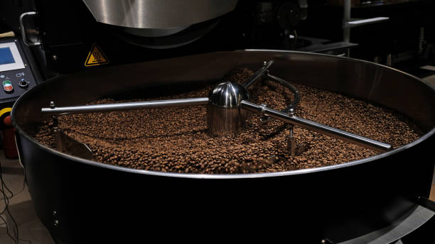 kaffeeröstmaschine bei kaffeeröstung. mischen von kaffeebohnen. geröstete spinning-kühler professionelle maschinen und frische braune kaffeebohnen bewegung nahaufnahme dunkles foto in der fabrik. - caffeine free stock-fotos und bilder