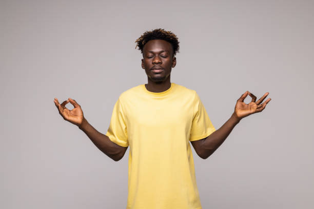 istock Young man meditating, eyes closed, isolated grey wall background. Stress relief techniques at work concept. Take a deep breath. 1341621882