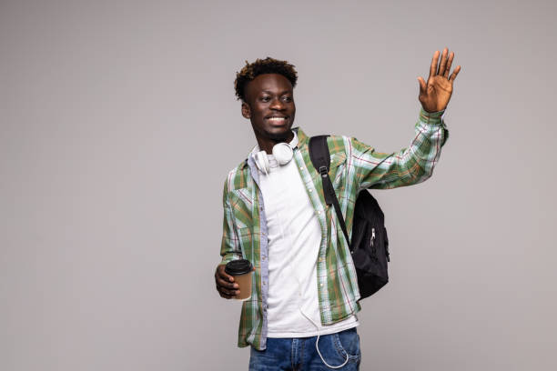 istock Young african man student with backpack wave with hands isolated on white background 1341621919