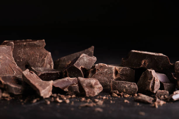 istock Pieces of dark chocolate on black table, closeup 1341622517