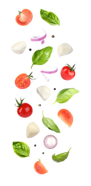 istock Mozzarella cheese, tomatoes, onion and basil leaves falling on white background 1341622596