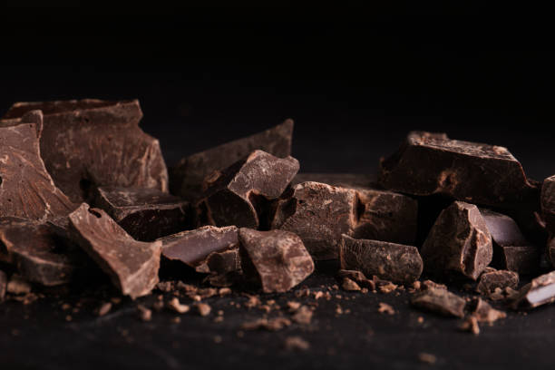 istock Pieces of dark chocolate on black table, closeup 1341622663