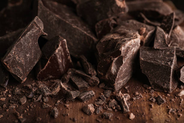 trozos de chocolate negro sobre mesa de madera, primer plano - brown chocolate candy bar close up fotografías e imágenes de stock