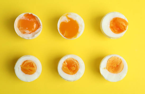 istock Different readiness stages of boiled chicken eggs on yellow background, flat lay 1341622858
