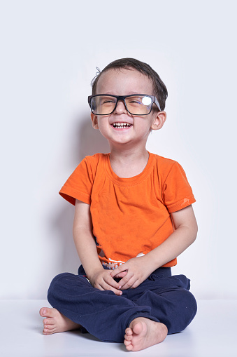 A cute little boy wearing big eyeglasses. Funny portrait of handsome 3-years-old multiracial kid. Cheerful child with big nerd eyeglasses