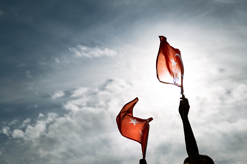 Dos manos sosteniendo banderas turcas en un cielo azul y nublado y en el día de la libertad Izmir photo