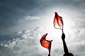 Two Hands holding Turkish flags on a blue and cloudy sky and on the day of liberty Izmir