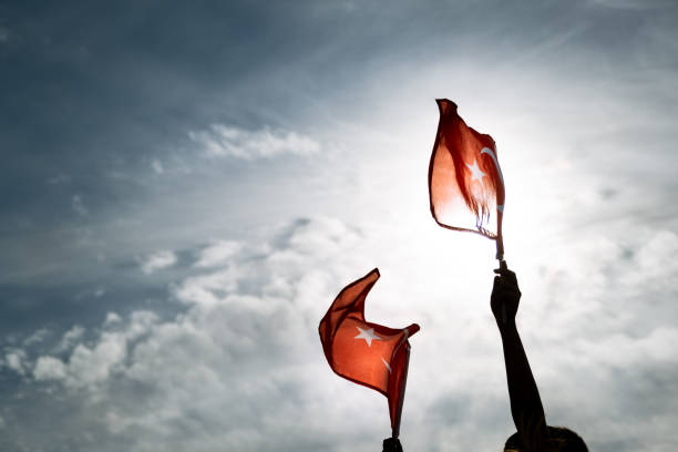 Two Hands holding Turkish flags on a blue and cloudy sky and on the day of liberty Izmir stock photo
