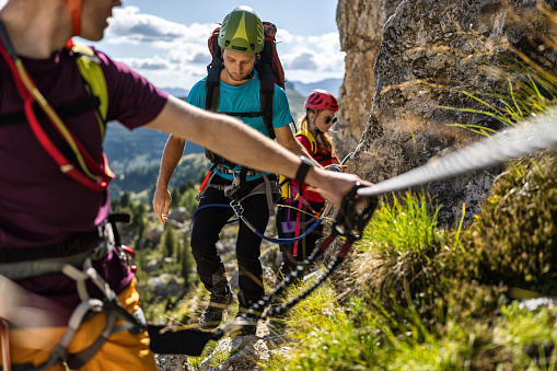 Alpine mountain guide climbing on via ferrata with hiking group