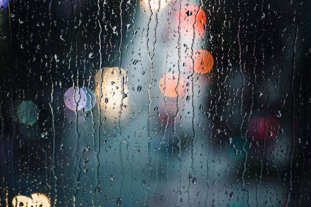 istock Abstract raindrops on window with colorful bokeh from city traffic 1341627644