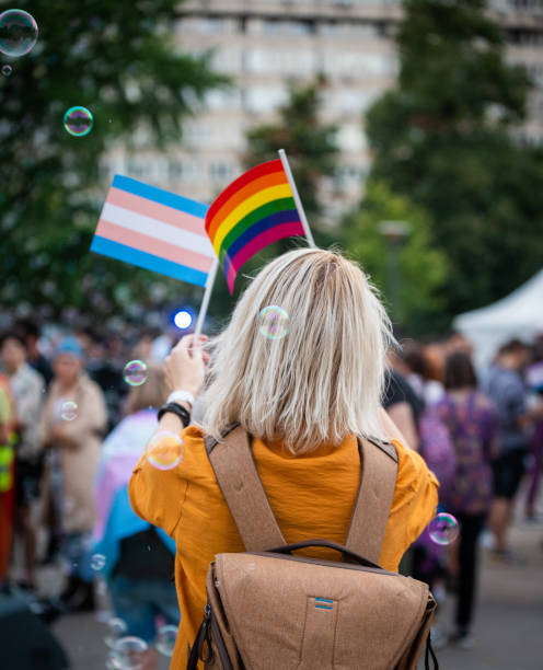 женщина размахивает флагами rainbow pride на фестивале любви - gay pride стоковые фото и изображения