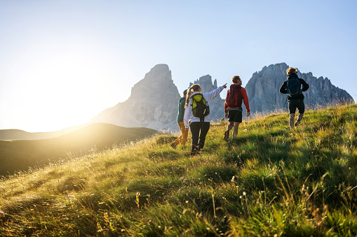 Storytelling of a day of hiking and climbing on the Dolomites: Group of friends hiking on the mountain at sunset
