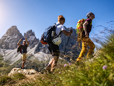 Storytelling of a day of hiking and climbing on the Dolomites: Father photographing his sons hiking on the mountain