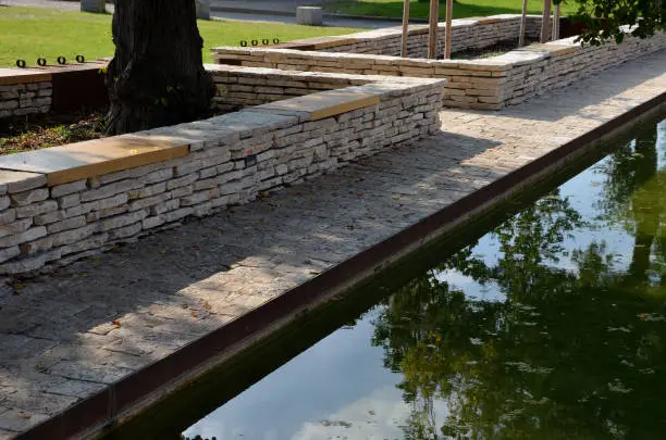 stone marl walls with stone cladding by the pool, ponds, fire tanks. metal bike racks and trash cans included in the wall. rusty corten steel railing, beige lime pavement, cor-ten, marl,